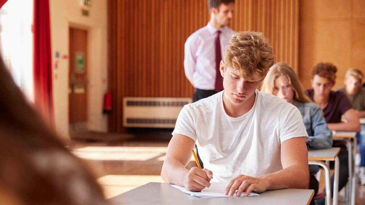 invigilator next to students taking an exam