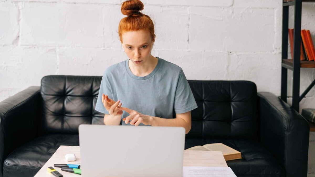 Woman with red head sitting on a couch working on a computer