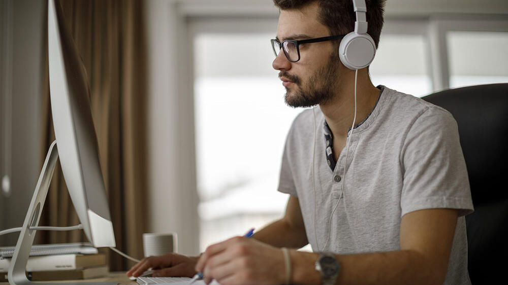 Man working on a computer at his desk with headphones